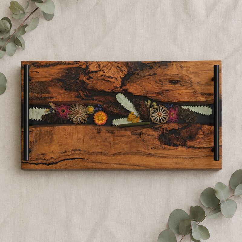 Handmade Australian wildflower timber and resin charcuterie board with a dark botanical channel and black handles.
