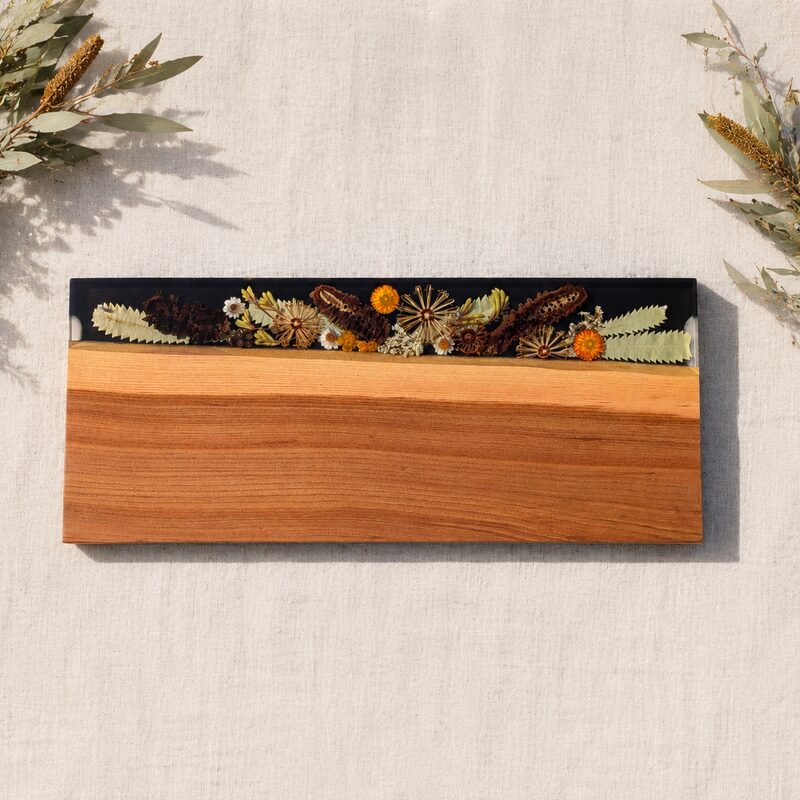 Large two-tone Australian timber serving board featuring preserved native botanicals encased in dark resin.