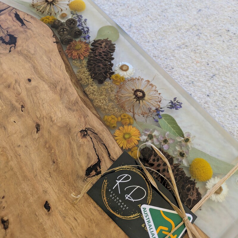 Elevate your home or gift-giving experience with our 100% Australian-made handcrafted serving board, a masterpiece of timber, resin, and dried native flora. Each board is meticulously crafted to not only serve as a functional piece but also as a captivating storyteller of the Australian bush. Experience the charm and craftsmanship of our 100% Australian-made serving board today. Order now and bring home a piece of the Australian bush that tells a story of artistry, sustainability, and natural beauty.