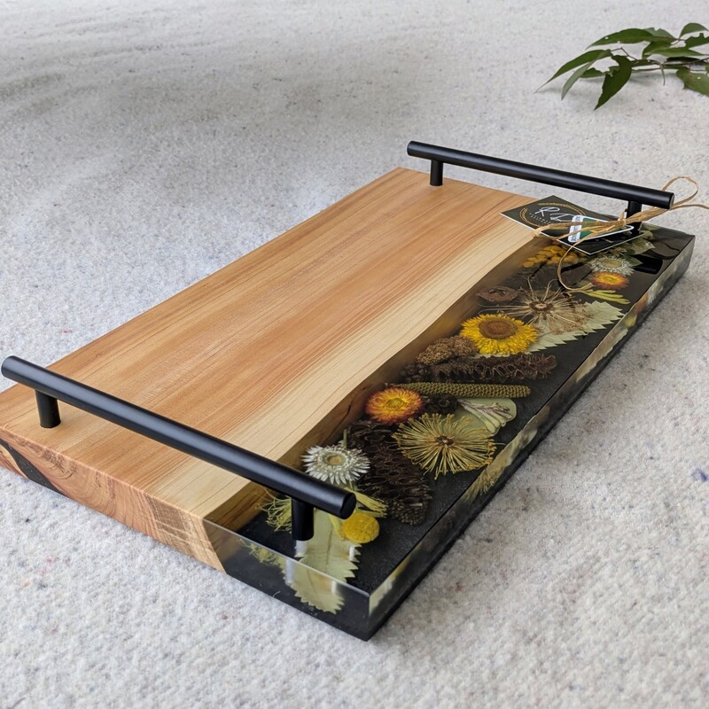 Celebrate Australia with our handcrafted serving platter. Made from locally sourced timber, resin, and dried Australian flora, it serves as a functional cheese board and a showcase of Australia’s beauty. Perfect for gifting, each board blends native timber with translucent resin and preserved flora, capturing the essence of our landscapes. Presented in elegant packaging, it’s a thoughtful gift ready for worldwide shipping.