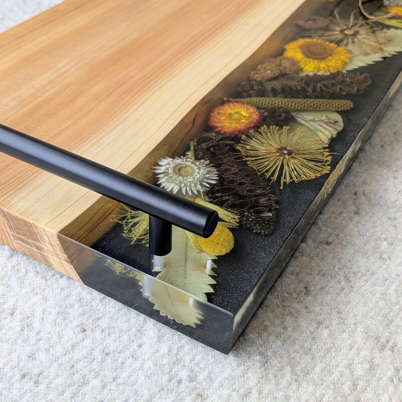 Celebrate Australia with our handcrafted serving platter. Made from locally sourced timber, resin, and dried Australian flora, it serves as a functional cheese board and a showcase of Australia’s beauty. Perfect for gifting, each board blends native timber with translucent resin and preserved flora, capturing the essence of our landscapes. Presented in elegant packaging, it’s a thoughtful gift ready for worldwide shipping.
