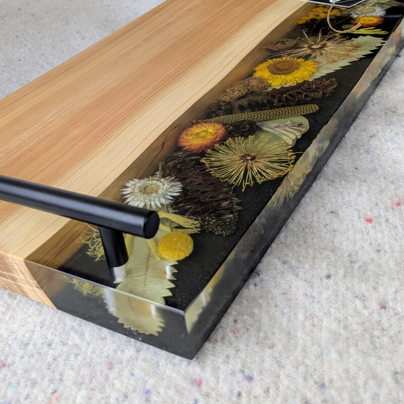Celebrate Australia with our handcrafted serving platter. Made from locally sourced timber, resin, and dried Australian flora, it serves as a functional cheese board and a showcase of Australia’s beauty. Perfect for gifting, each board blends native timber with translucent resin and preserved flora, capturing the essence of our landscapes. Presented in elegant packaging, it’s a thoughtful gift ready for worldwide shipping.