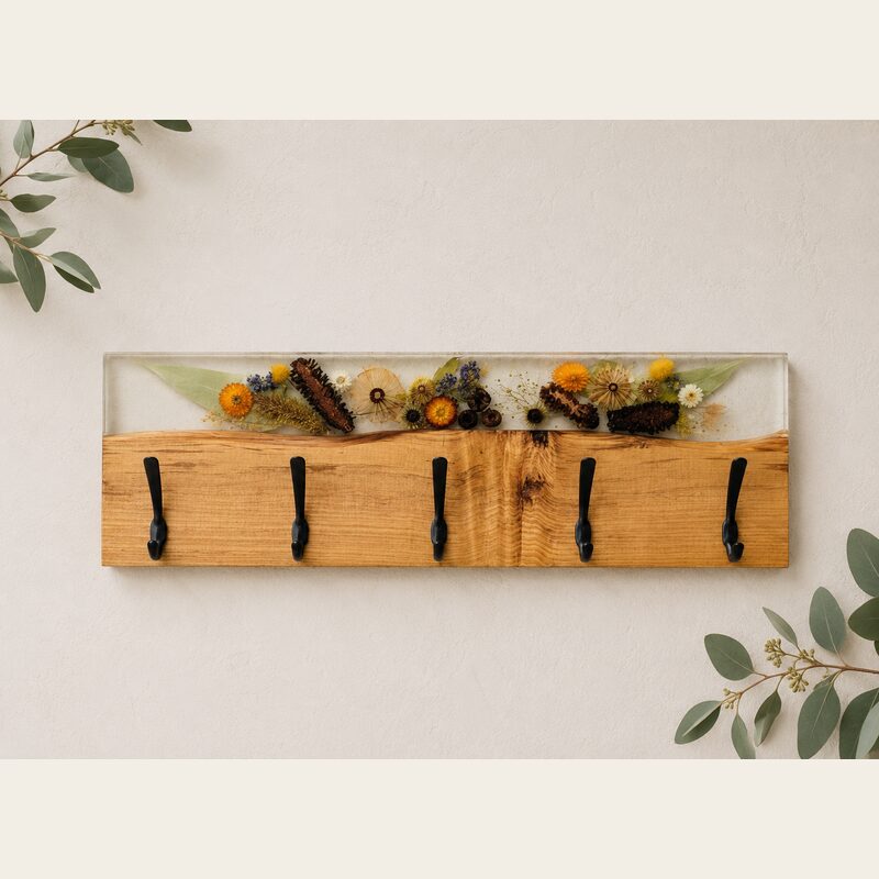 Handcrafted Australian timber and botanical resin coat rack with five black hooks on a warm neutral wall.