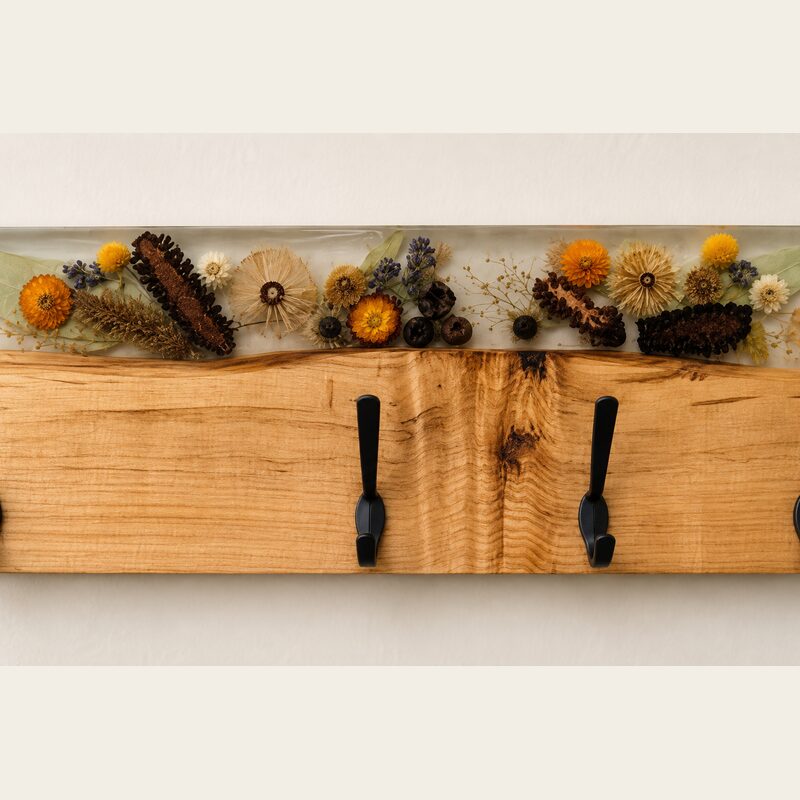 Close-up of preserved native botanicals in clear resin, natural timber grain and matte-black coat hooks.