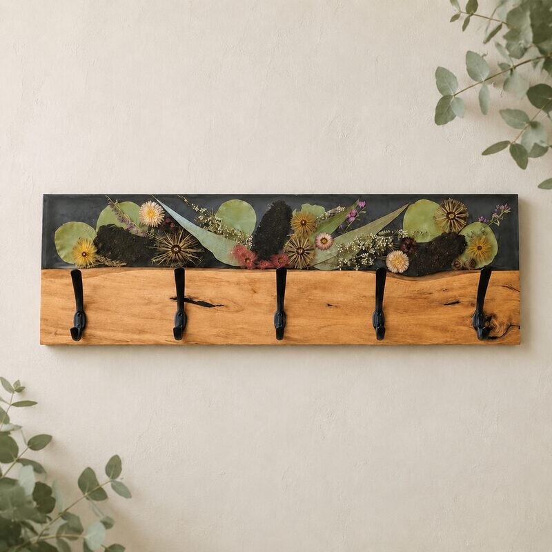 Handcrafted Australian timber and dark botanical resin coat rack with five black hooks on a warm neutral wall.