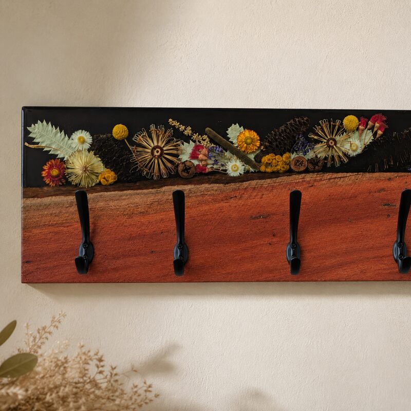 Close-up of rich Australian red gum, preserved native botanicals, black resin and handcrafted coat hooks.